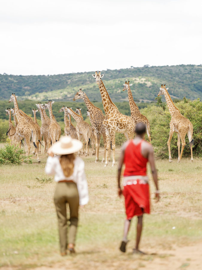 people on a walking safari with giraffe in the background