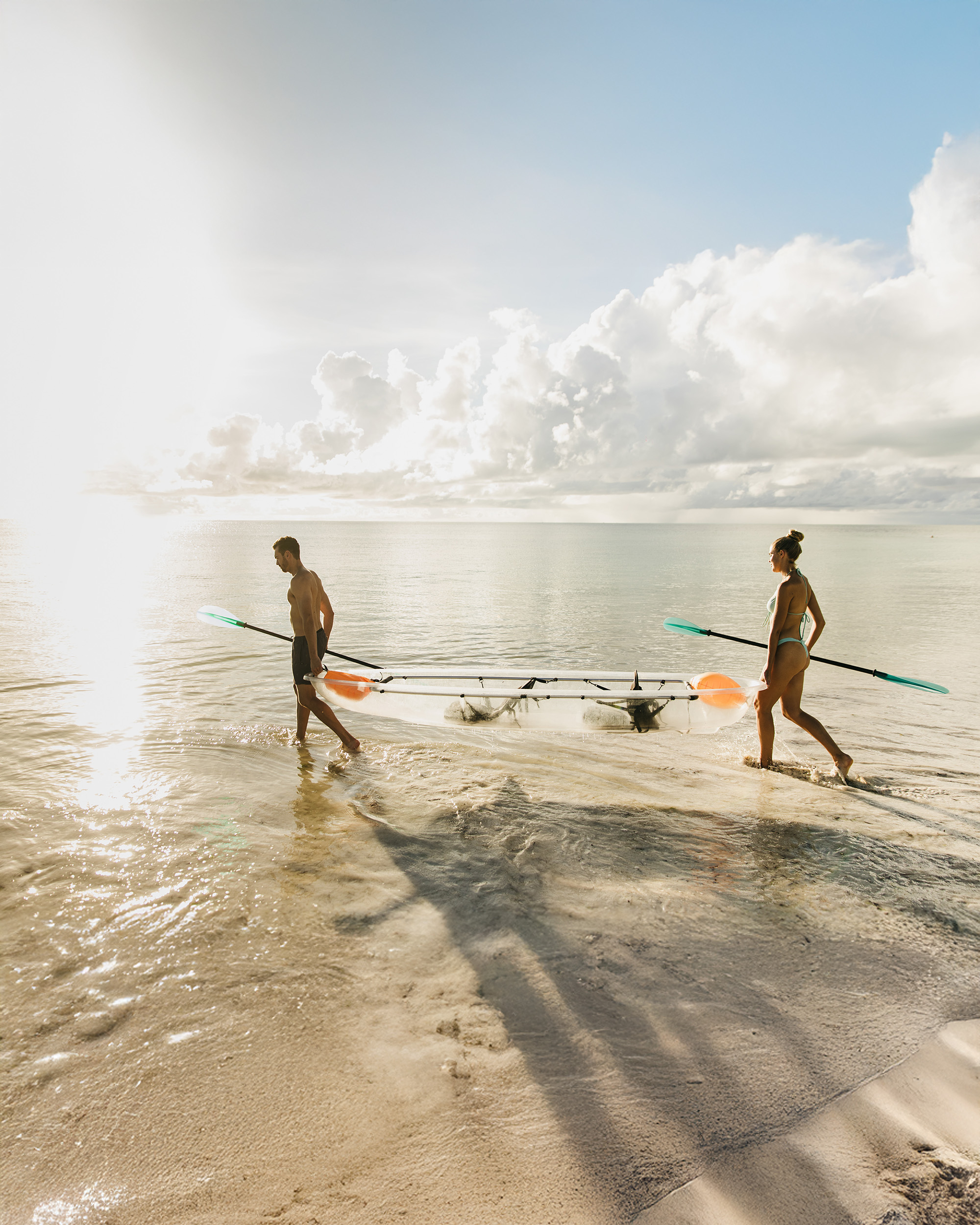 a couple carrying a small boat by the water